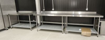 une cuisine équipée de plans de travail en inox et d'un réfrigérateur