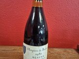 une bouteille de vin posée sur une table en bois, près d'un mur rouge