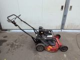 an image of a lawn mower parked in front of a garage