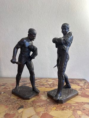 une paire de figurines en bronze représentant un homme et une femme, posées sur une table en marbre