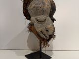an image of a wooden mask on a stand on a white surface