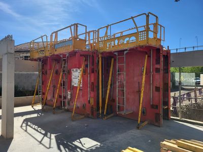 un chantier de construction avec un bâtiment rouge et des échafaudages jaunes