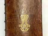 un vieux livre orné d'une couronne dorée, posé à côté d'une règle