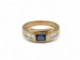un gros plan d'une bague en or sertie d'un saphir bleu et de diamants taille baguette