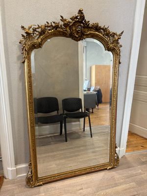 un grand miroir posé par terre à côté d'une chaise
