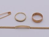 a gold bracelet, ring, and other jewelry on a white surface