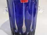 un vase en verre bleu sur lequel est collée une étiquette rouge