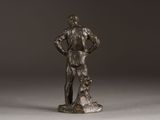 bronze statue of a man standing with his hands on his hips