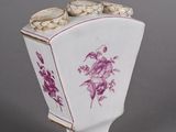 a white vase with pink flowers on it on a gray surface