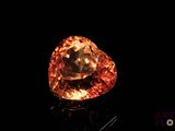 un gros plan d'un gros diamant orange sur une surface noire