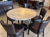 tables and chairs are arranged around a round table in a restaurant
