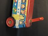 a red and blue toy bus with wheels on a black surface
