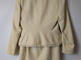 the back of a beige jacket hanging on a hanger