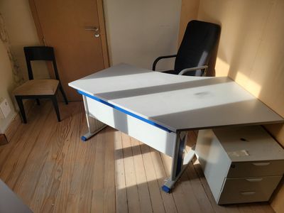 a white desk with a black chair in the corner