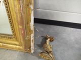 a gold frame with a mirror on the floor next to it