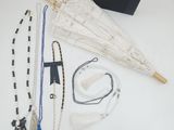 un parapluie blanc, des colliers, des bracelets et un sac à main posés sur une table