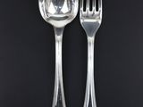 two silver spoons and a fork on a black background