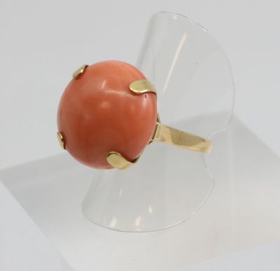 coral and gold ring on clear acrylic stand