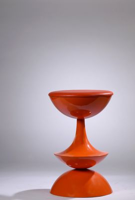 an orange vase sitting on top of a white table next to a gray wall