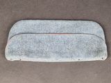 un gros plan d'une trousse en feutre gris posée sur une surface marron