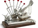 a silver sculpture of a bird and a basket of pins