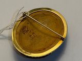 a gold brooch with a pin in the middle of it