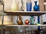de nombreux vases et verres posés sur une étagère dans une pièce