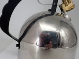 a silver tea kettle with a black handle on a white surface