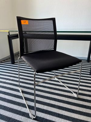 une chaise de bureau noire placée devant une table en verre