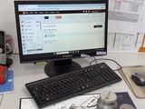 une personne assise à un bureau, devant un clavier et un écran