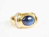 gros plan d'une bague en or avec une pierre bleue et des diamants