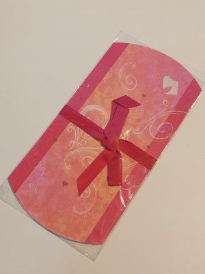 une carte rose ornée d'un nœud rouge, posée sur une table