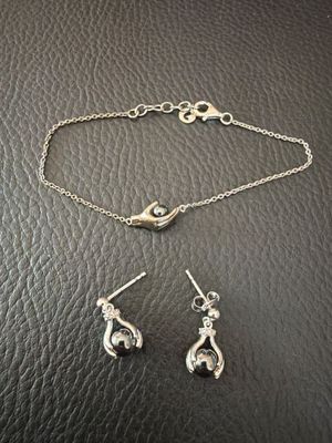 un gros plan d'un bracelet et de boucles d'oreilles en argent posés sur une surface noire