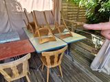 a person pointing at a table and chairs on a deck