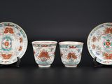 trois tasses et soucoupes en porcelaine chinoise posées sur des socles, sur fond noir