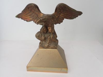 statue d'un aigle posée sur un socle, sur une surface blanche