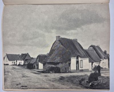 une vieille photo d'un village avec des toits de chaume et un chemin de terre