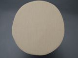 an upholstered round ottoman with a beige fabric cover