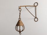 une cloche en laiton suspendue à un crochet fixé au mur