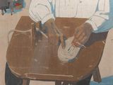 a painting of a man sitting at a table with a shoe