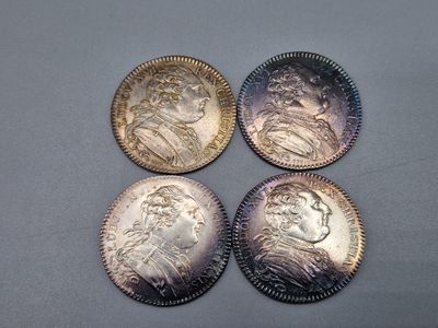 quatre types de pièces différents posés sur une table avec un fond gris
