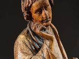 a wooden statue of a man holding a book and a book