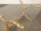 a glass table with a gold metal snake on it