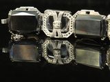 three silver cuff bracelets on a black surface with a black background