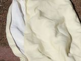 a white blanket on the ground next to a black and white cat