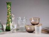 a green glass vase sitting on a table next to other glassware