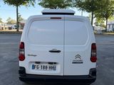 une camionnette blanche garée sur un parking avec des arbres en arrière-plan