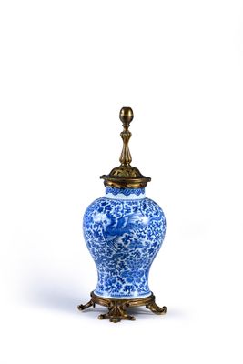a blue and white vase with a gold lid on a stand