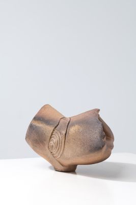 a small bronze object on a white surface