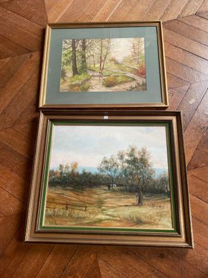two framed paintings of a landscape on a wooden floor